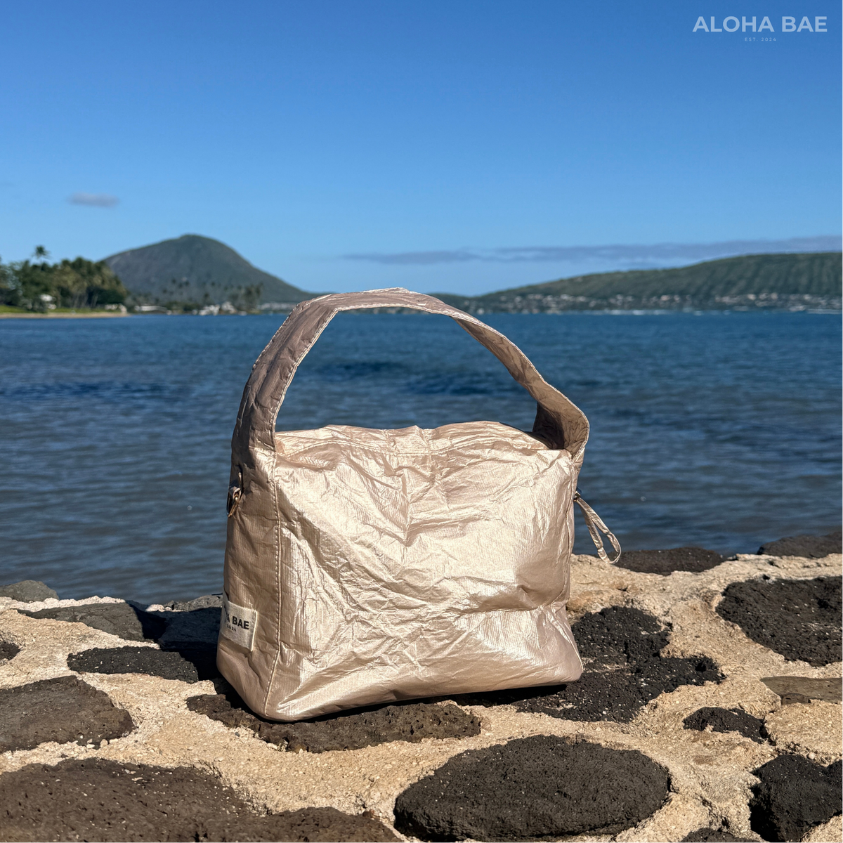 Aloha Bae Champagne Hobo Bag by alohabae featuring a stylish, structured bag with a metallic champagne finish and shoulder strap.