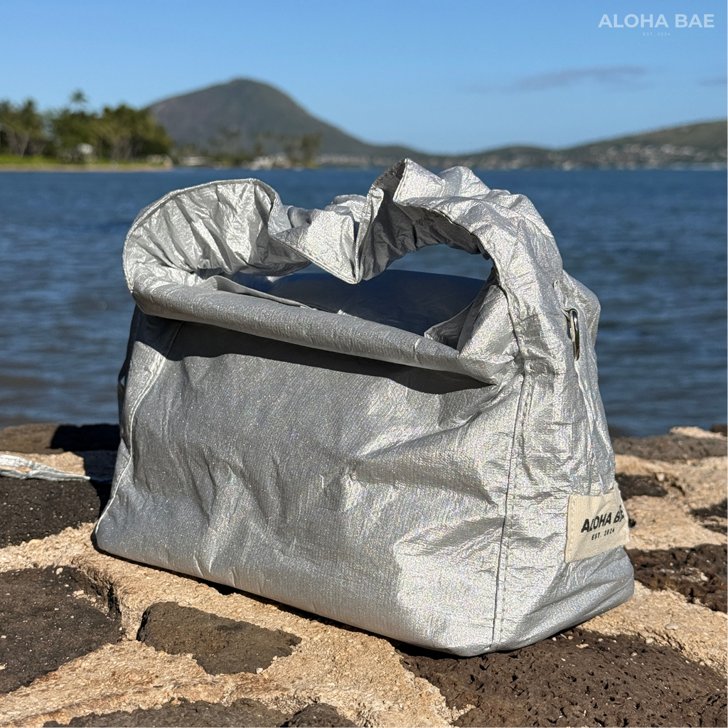 Silver Aloha Bae hobo bag with shoulder strap and stylish design, made by alohabae, displayed on a plain background.